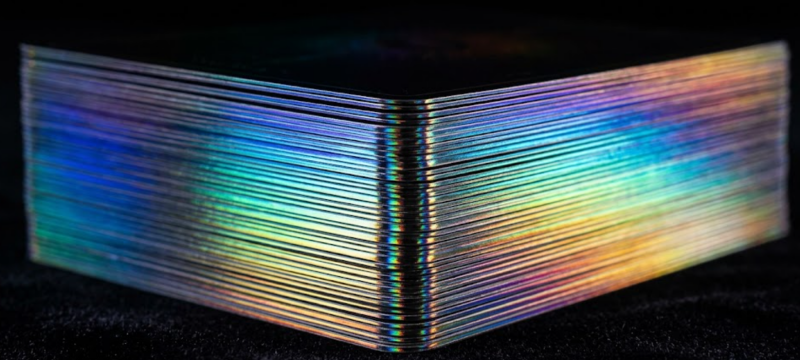 Extreme macro view of flake-free holographic edge gilding on a tarot deck, processed with 0.1mm micro-sanding.